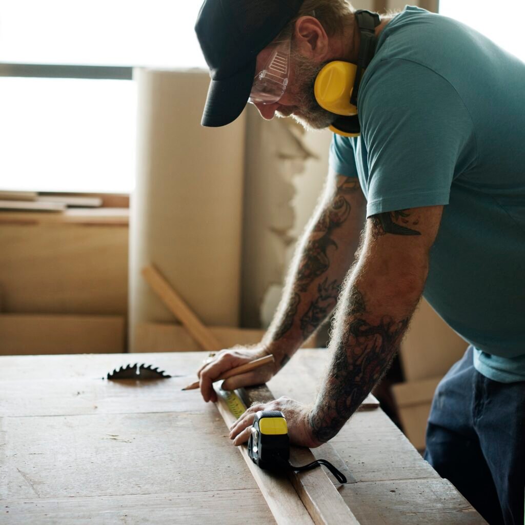 Carpenter using pencil and measurement tape on wood