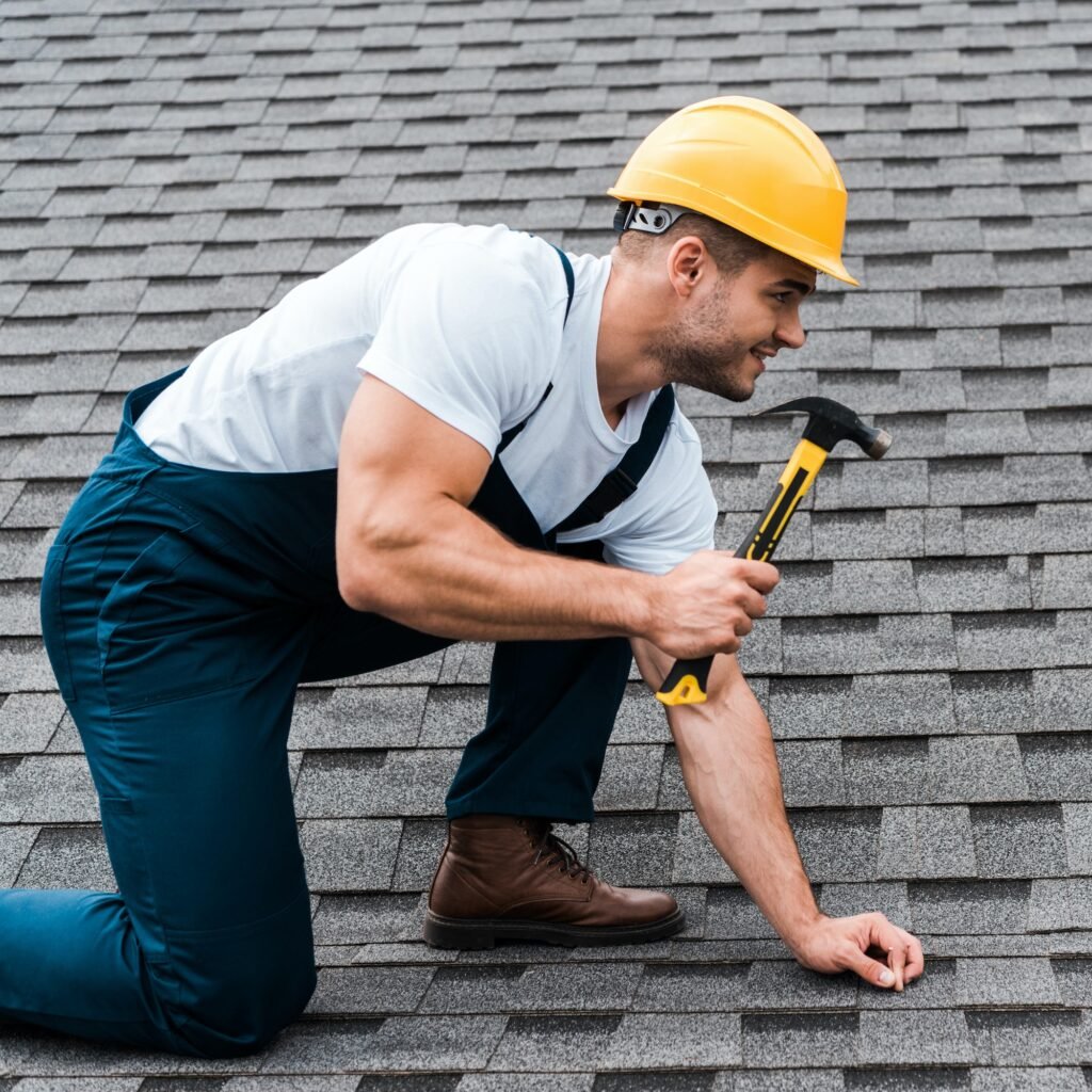 repairman in helmet holding hammer while repairing roof in house